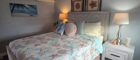 Un dormitorio con cama, mesita de noche, decoración en la pared y equipo de aire acondicionado.