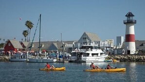 Ein Hafen mit Booten, einem Leuchtturm und Gebäuden entlang der Uferlinie.