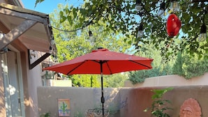 A patio with a table and chairs, a barbecue grill, and a decorative wall. - So. Capitol area quaint casita! Walk to Railyard & Plaza (Santa Fe)