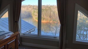 Una camera da letto con un'ampia finestra che si affaccia su un lago e una foresta.