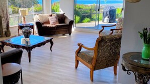 A spacious living room with a view of the ocean, a sofa, a chair, a coffee table, and a decorative table.