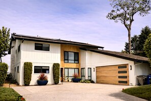 A two-story modern house with a garage, large windows, and well-maintained landscaping.