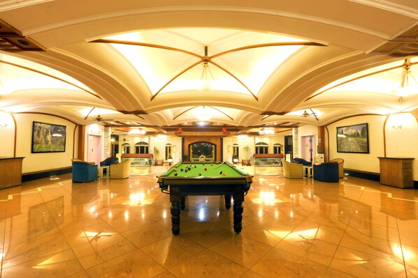 A spacious indoor pool area with a pool table in the center, surrounded by seating and a high ceiling with decorative lighting. - Kohinoor Samudra Beach Resort (Ratnagiri)