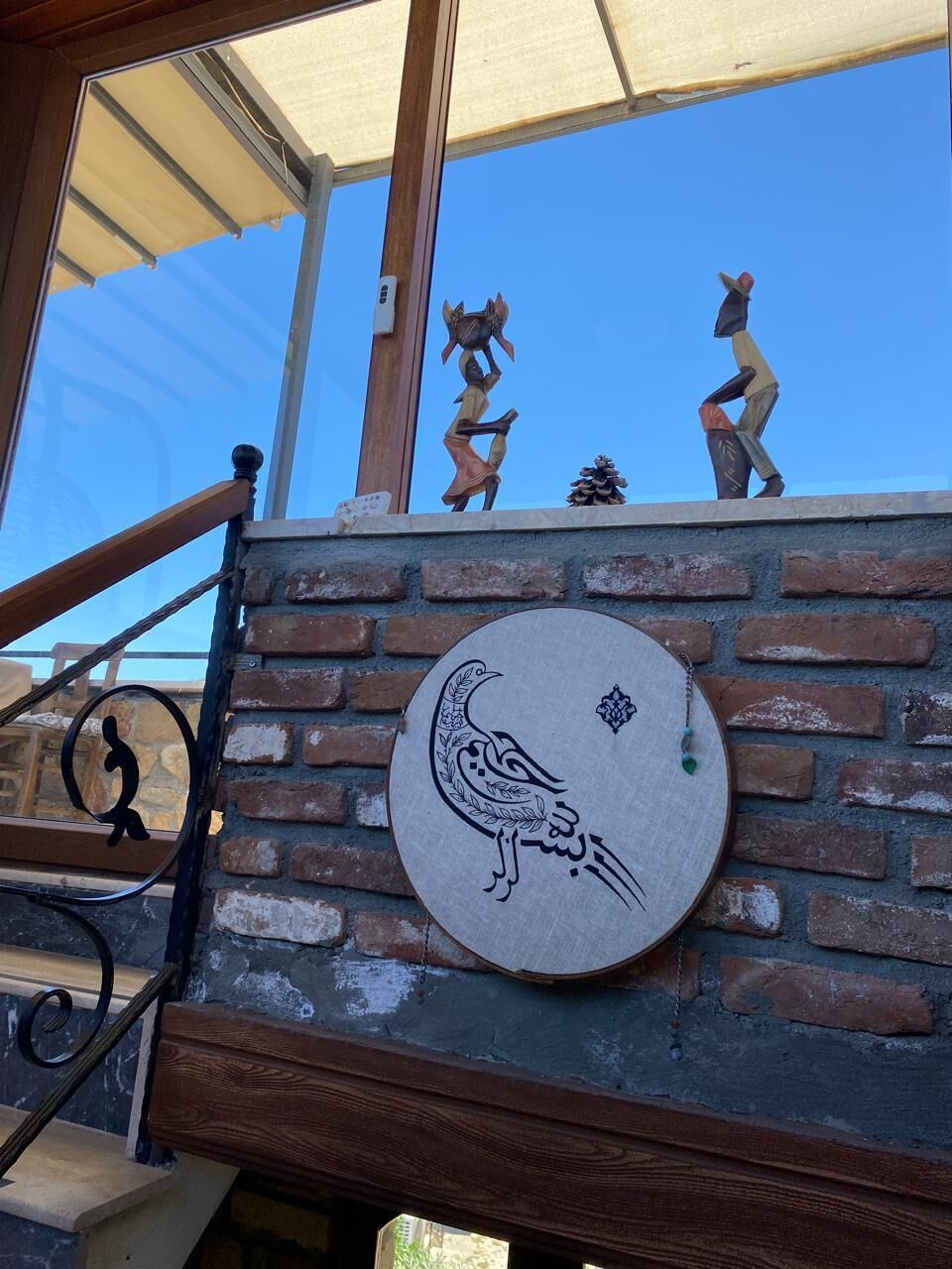 A staircase with a brick wall, a wooden handrail, and a circular sign with a bird design.