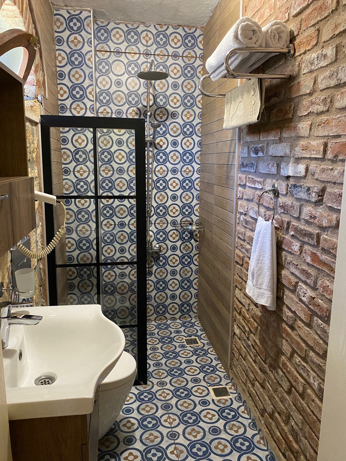 A bathroom with a shower, a sink, and a towel rack.