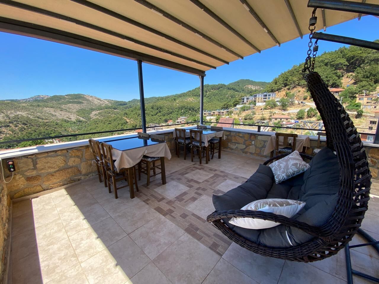 An outdoor patio with a hanging chair, dining table, and chairs.