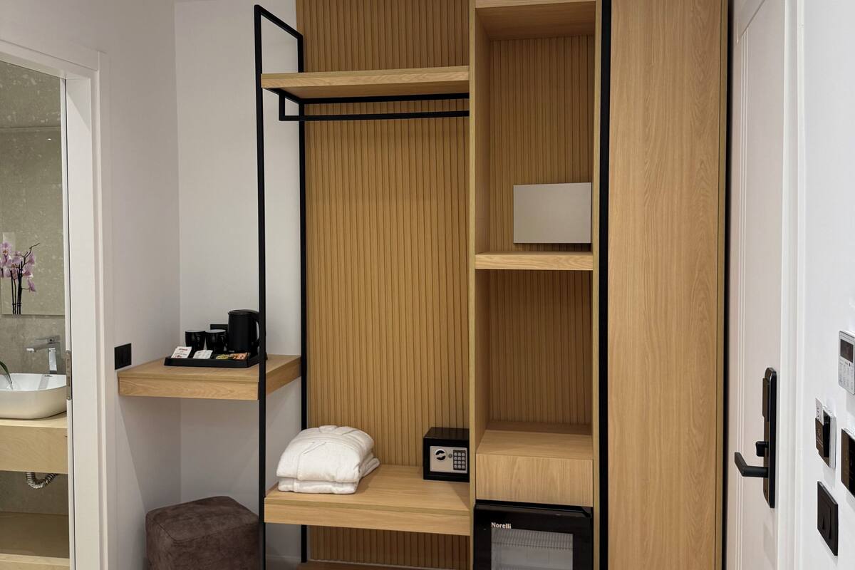 A modern room with a bunk bed, a small refrigerator, a coffee maker, and a bedside table.
