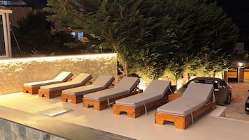 A poolside area with lounge chairs and a stone wall.