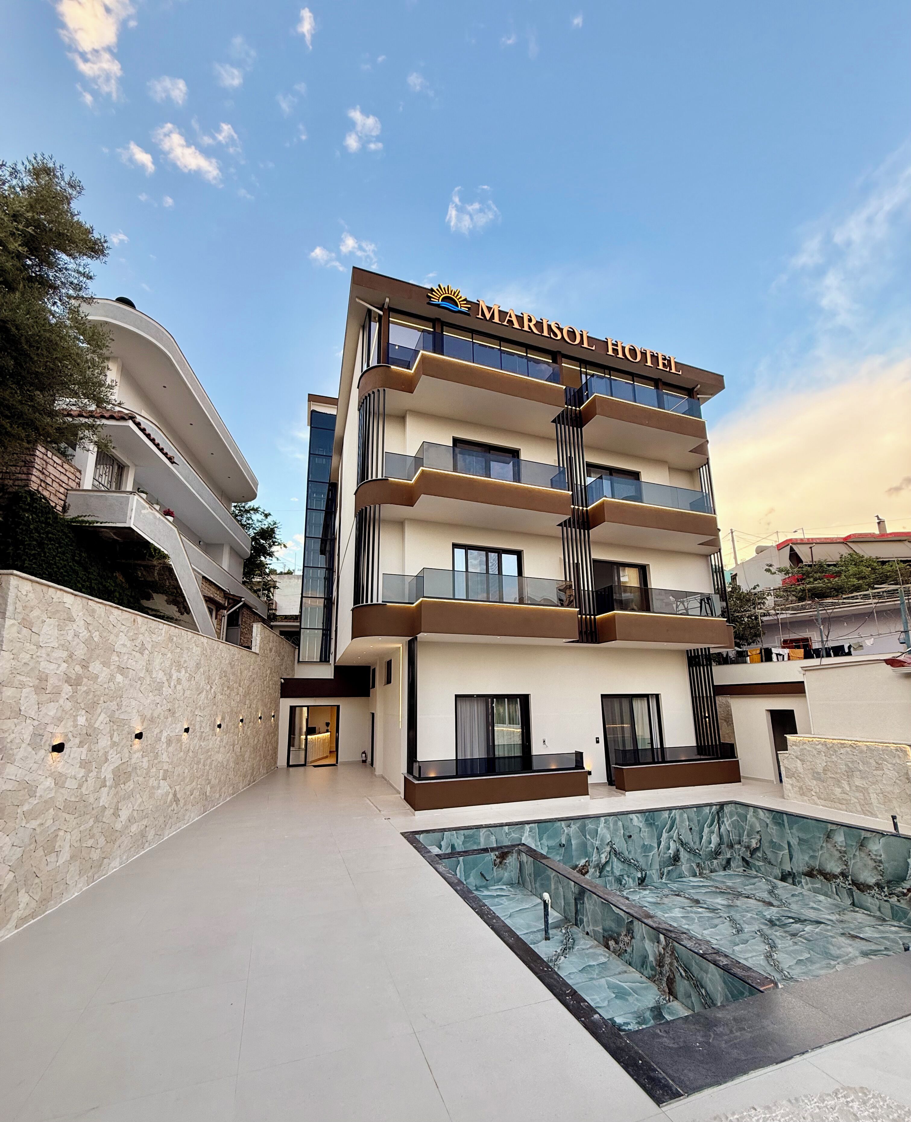 Un hotel de varios pisos con piscina, balcones y fachada de piedra.