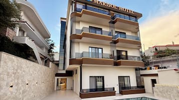 Un hotel de varios pisos con piscina, balcones y fachada de piedra.