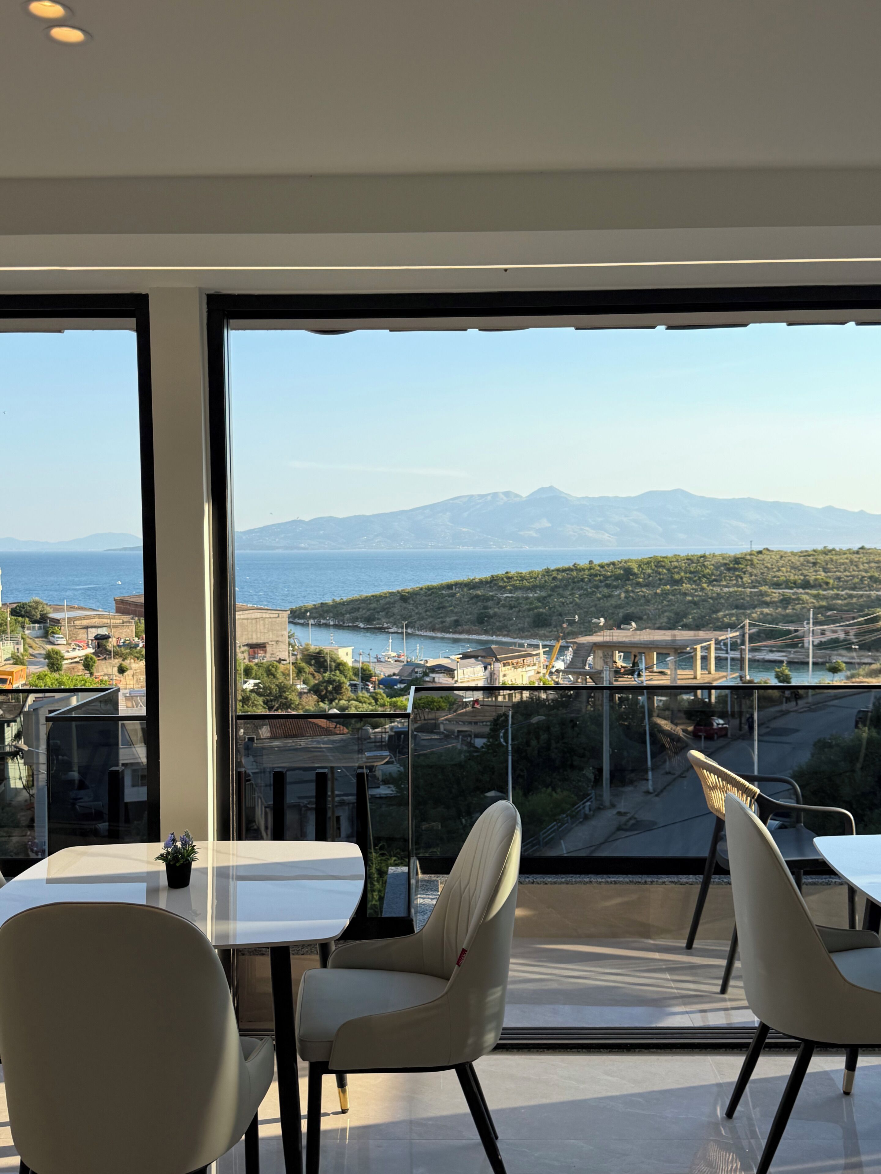 A modern room with large windows, a dining table, and two chairs.