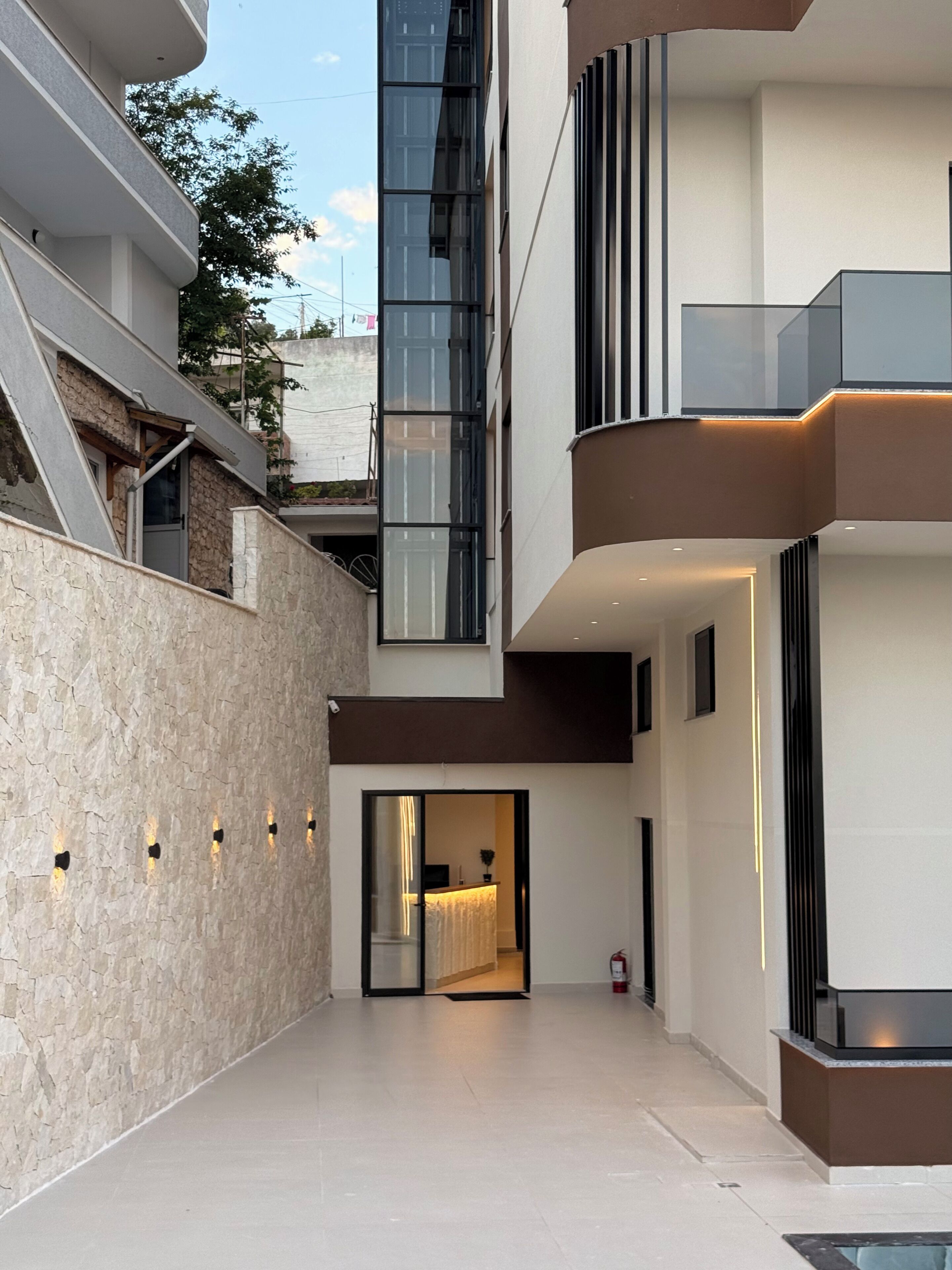A modern building with a glass facade, a balcony, and a door leading to an interior space.