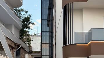 A modern building with a glass facade, a balcony, and a door leading to an interior space.