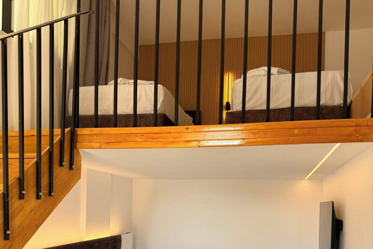 A hotel room with a bunk bed, a desk, and a TV.