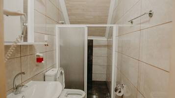 A small bathroom with a toilet, sink, and shower.