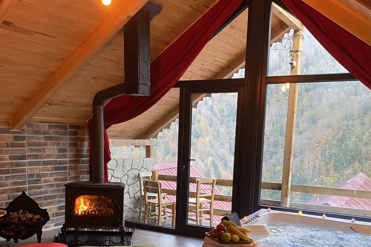 Una habitación acogedora con chimenea de piedra, un ventanal grande y un jacuzzi.