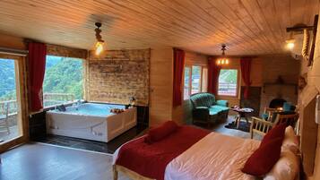 A wooden cabin with a large bed, a hot tub, and a fireplace.