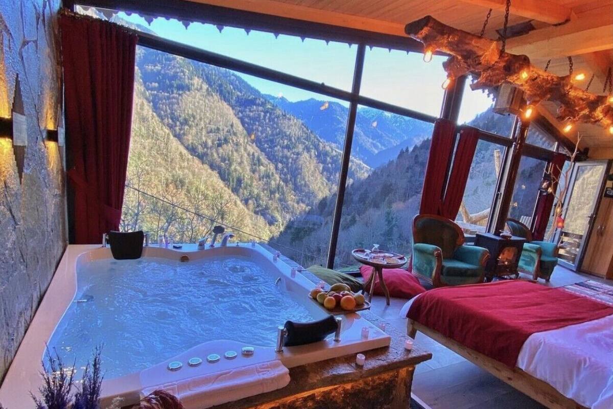 Una habitación con un ventanal grande, un jacuzzi, una cama y un comedor.