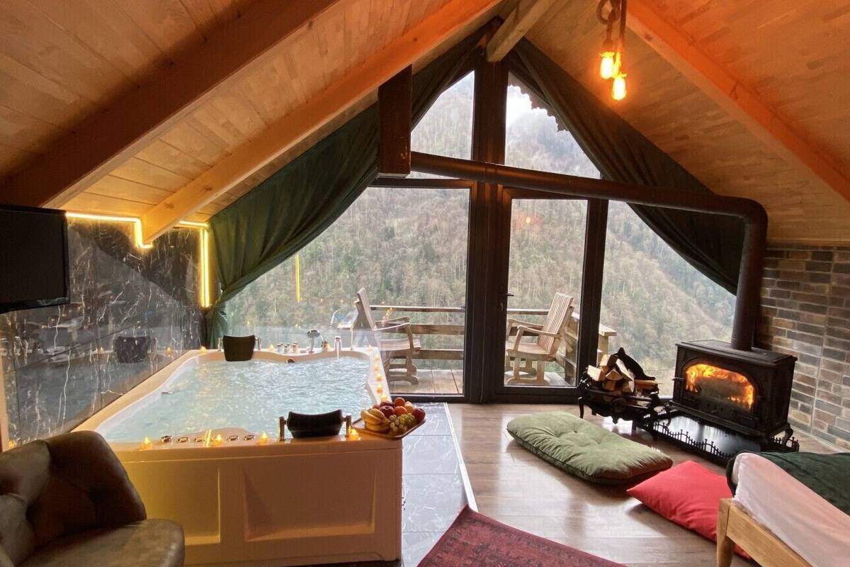 Acogedor cuarto ático con un amplio ventanal, chimenea, bañera y zona de estar.