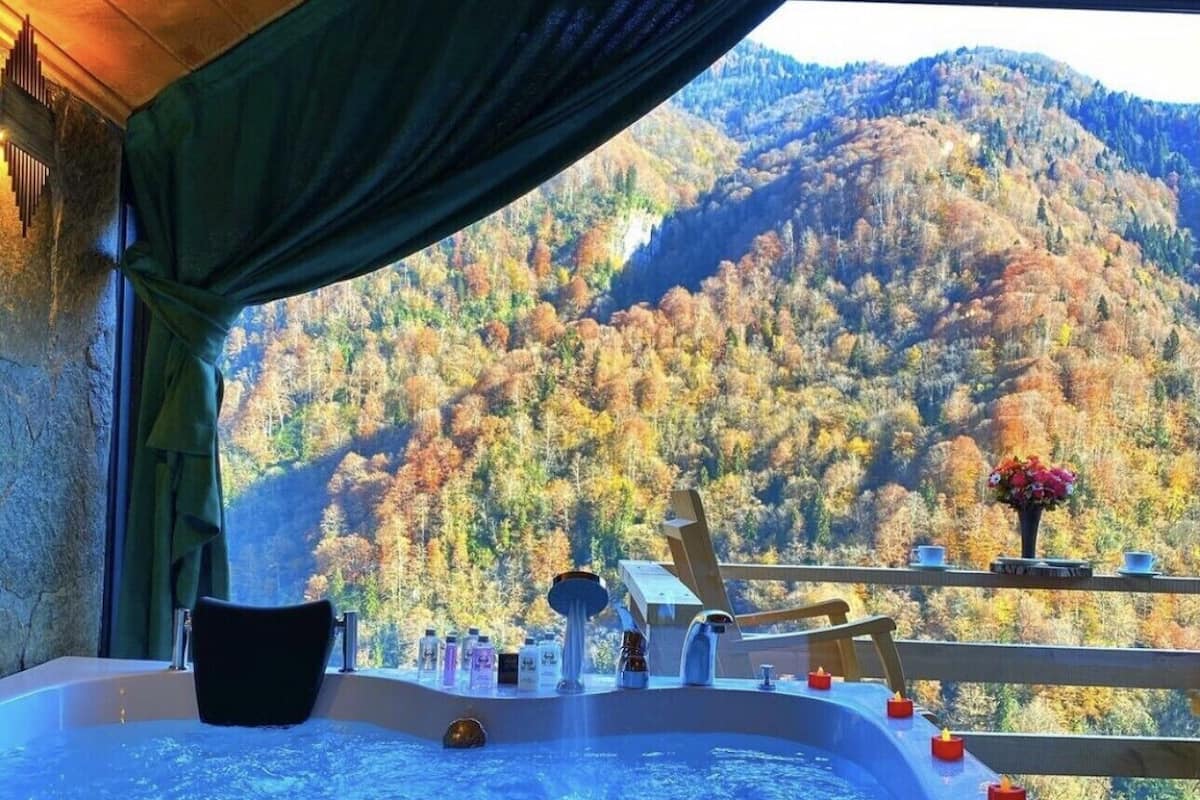 Un jacuzzi con vistas a una cadena montañosa boscosa.