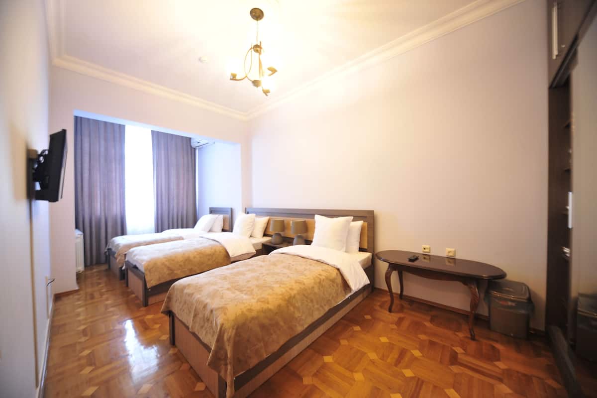 Ein Hotelzimmer mit zwei Betten, einem kleinen Tisch, einem Fernseher und einer Kristallleuchtre.