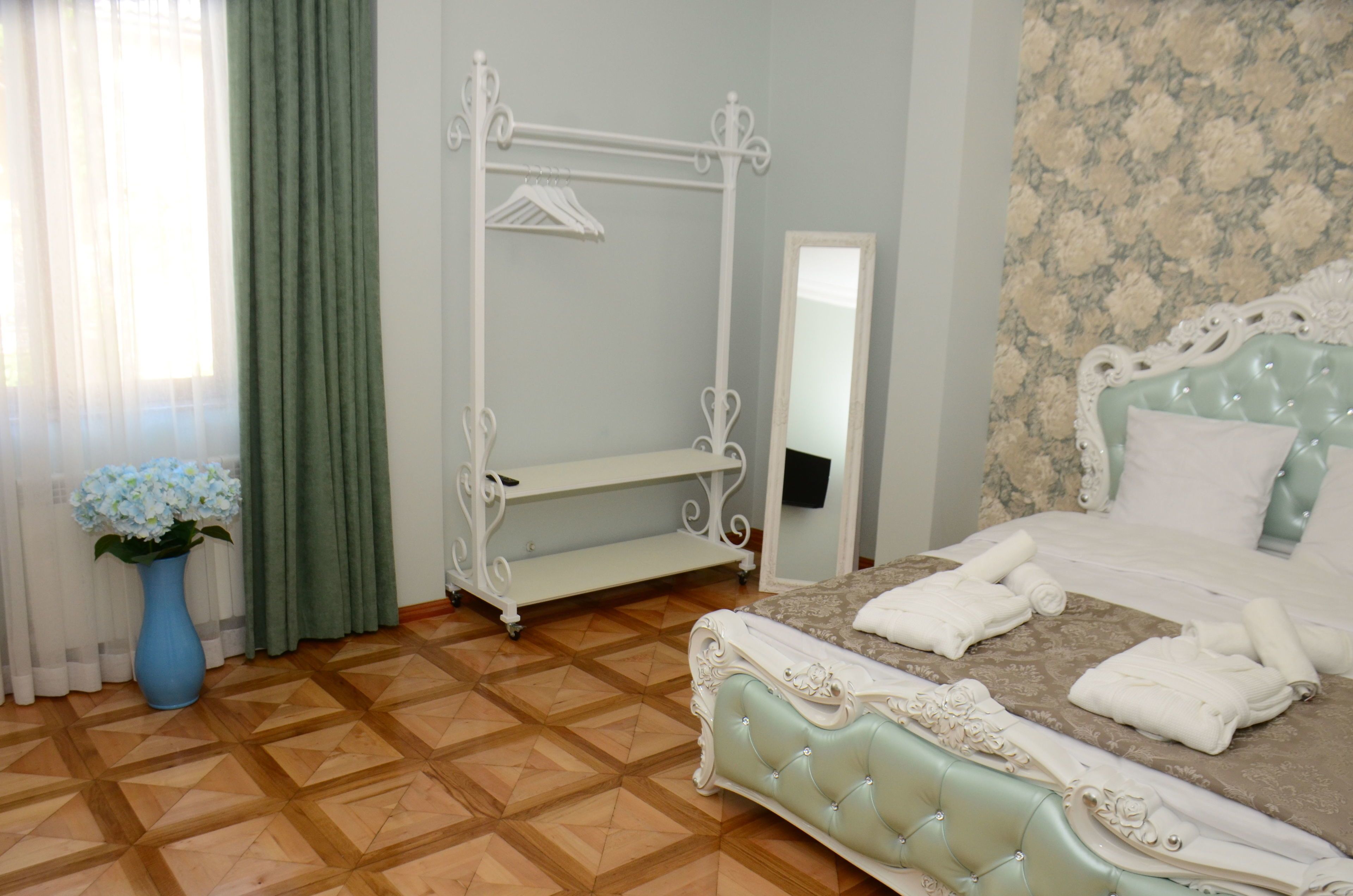 Quarto com cama, penteadeira com espelho, cabideiro e planta em vaso.