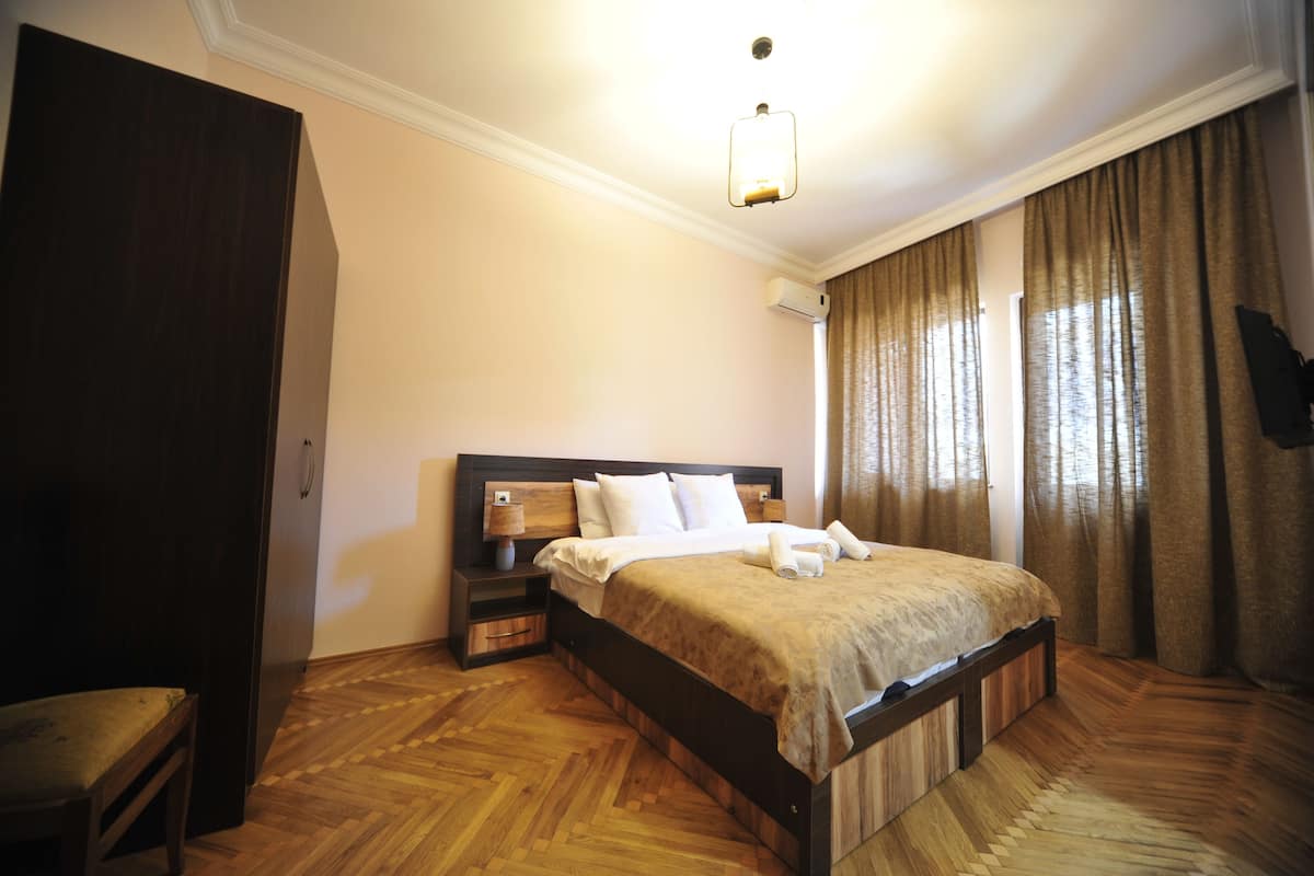 Ein Schlafzimmer mit einem hölzernen Bett, einem Nachttisch, einer Lampe und einem Kleiderschrank.