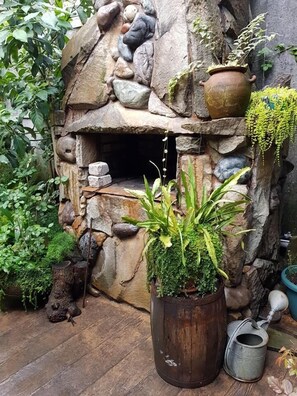 Ein rustikaler Kamin aus Stein mit einem Blumentopf davor.