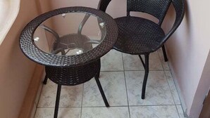 A small balcony with two wicker chairs and a glass-top table. - Guest House Batumi Globus (Batumi)