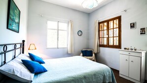 A bedroom with a bed, a dresser, a chair, and a window.