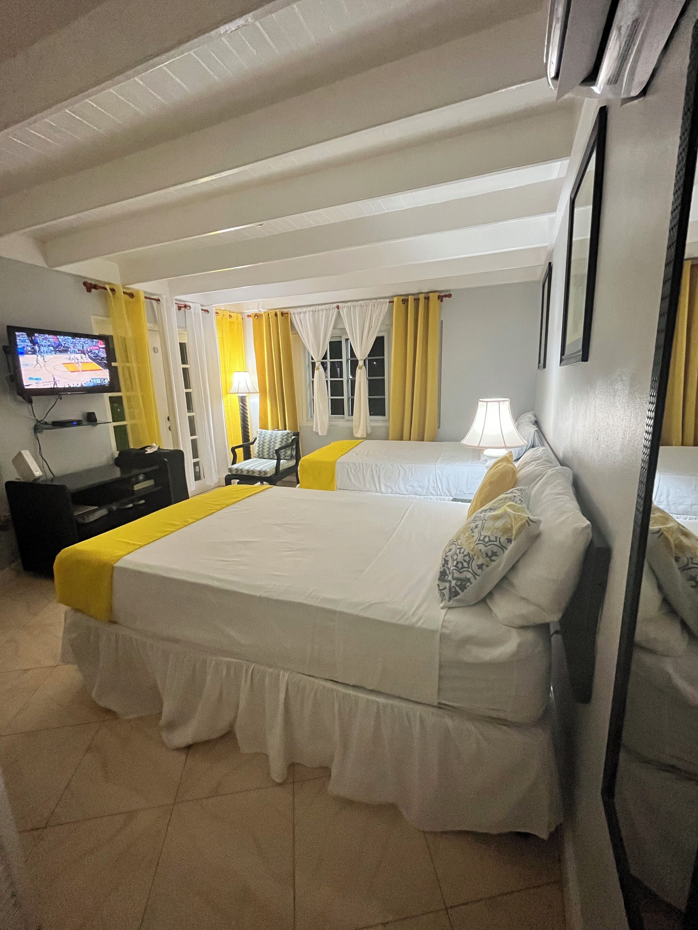 A hotel room with two beds, a television, a desk, and a chair.