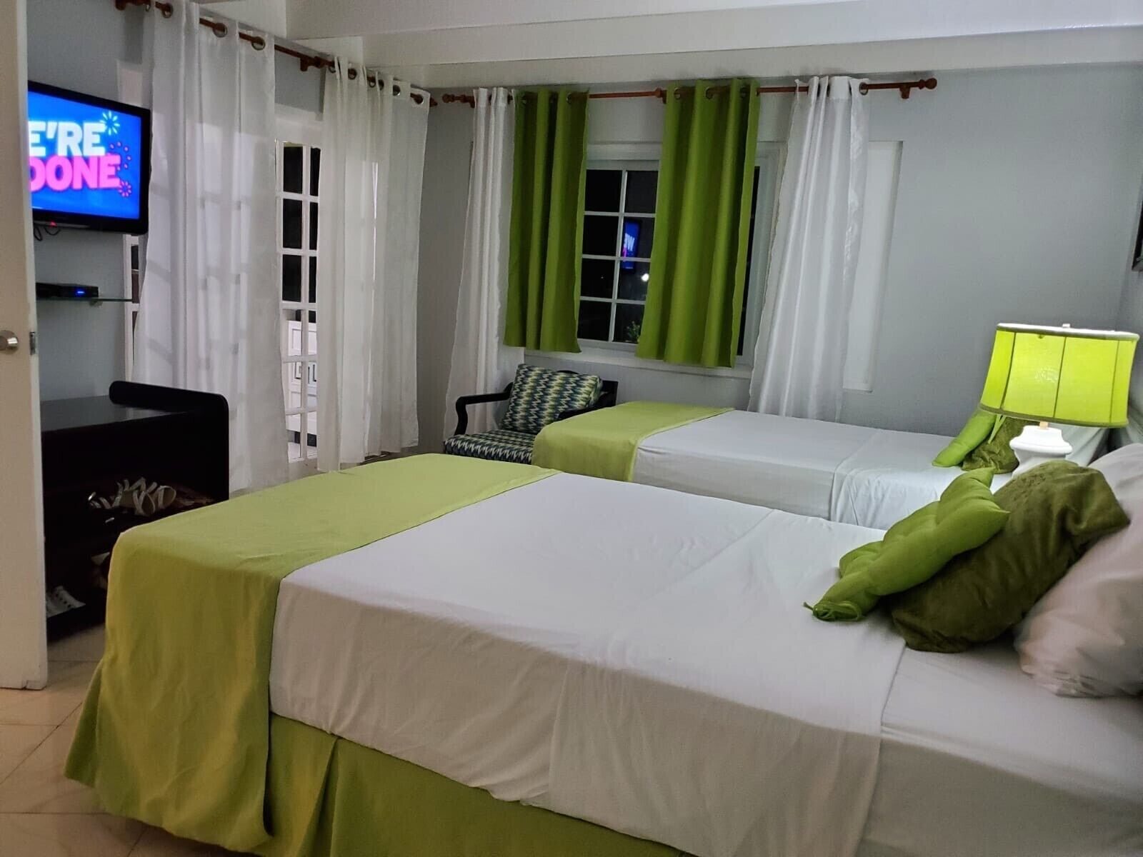 A hotel room with two beds, a TV, a desk, and a chair.