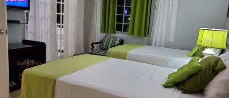 A hotel room with two beds, a TV, a desk, and a chair.