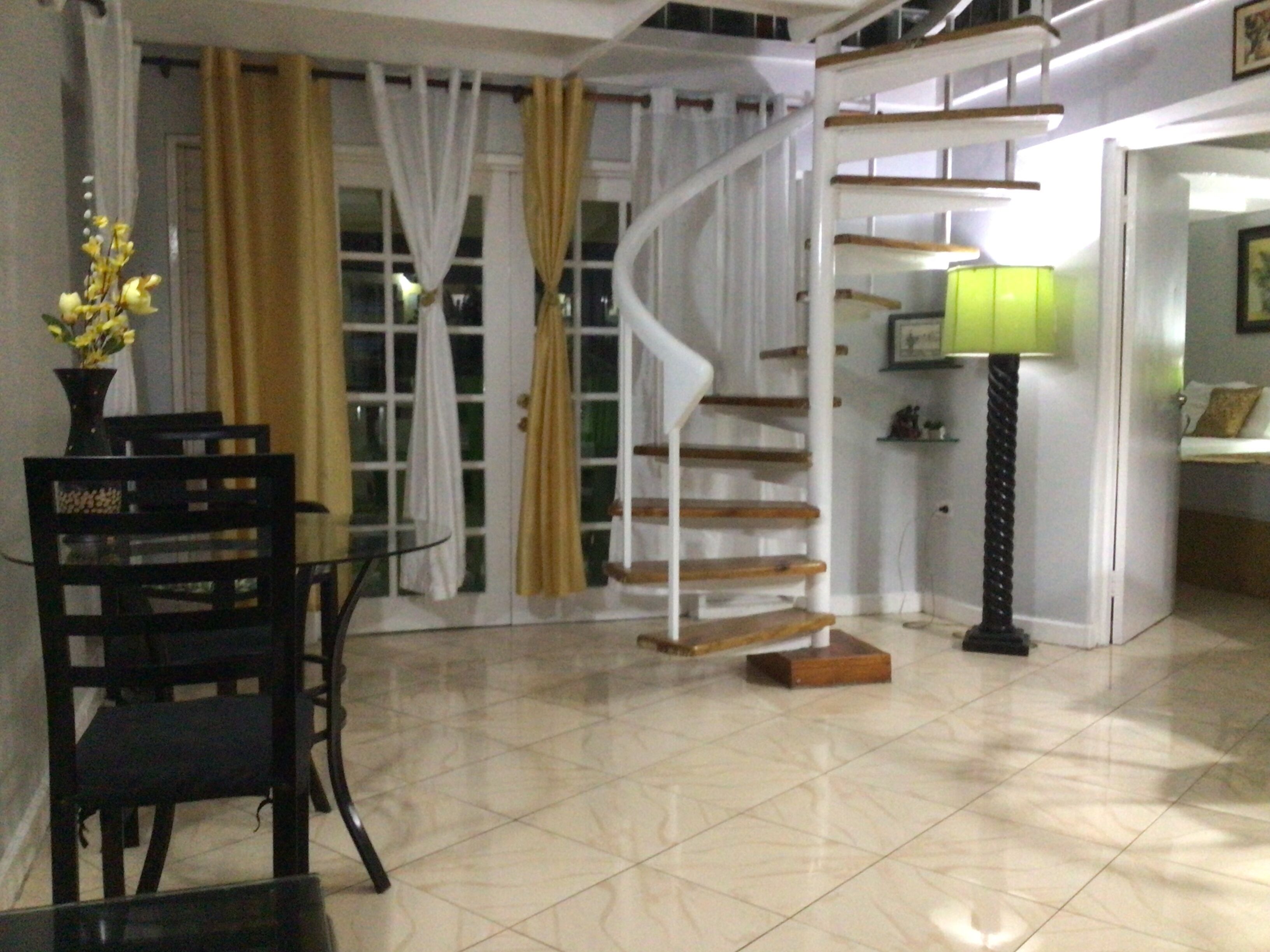 A staircase with a spiral design, a table with a vase of flowers, and a lamp.