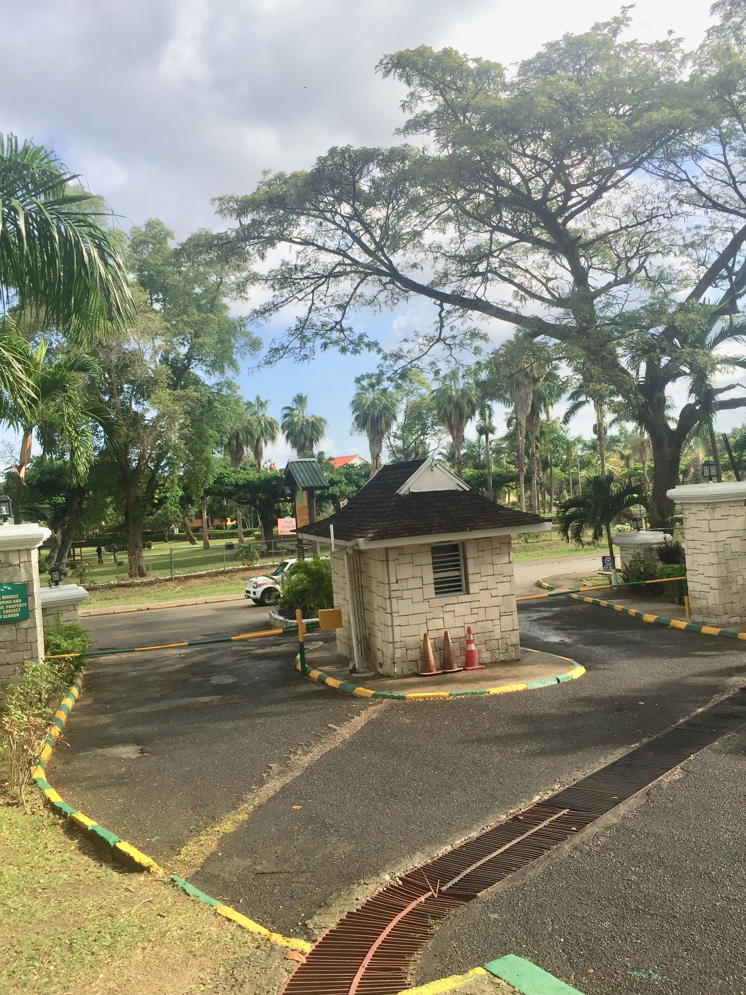 A gated parking area with a small building, palm trees, and a clear sky.