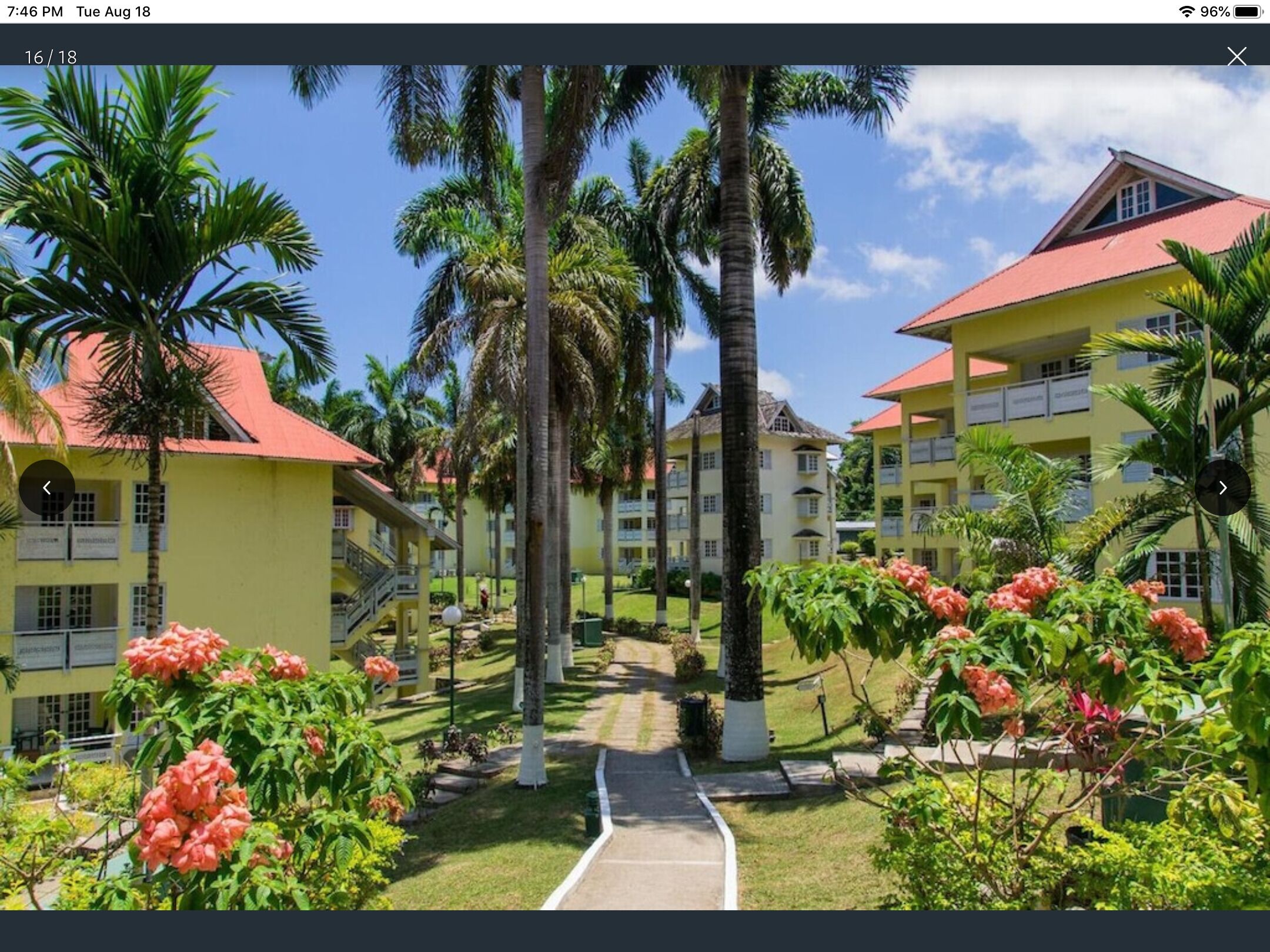 Un resort con varias edificaciones amarillas, palmeras y un cielo despejado.