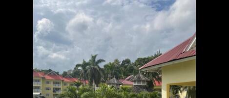 A residential area with multiple two-story buildings, some with red roofs, and a well-maintained lawn with palm trees.