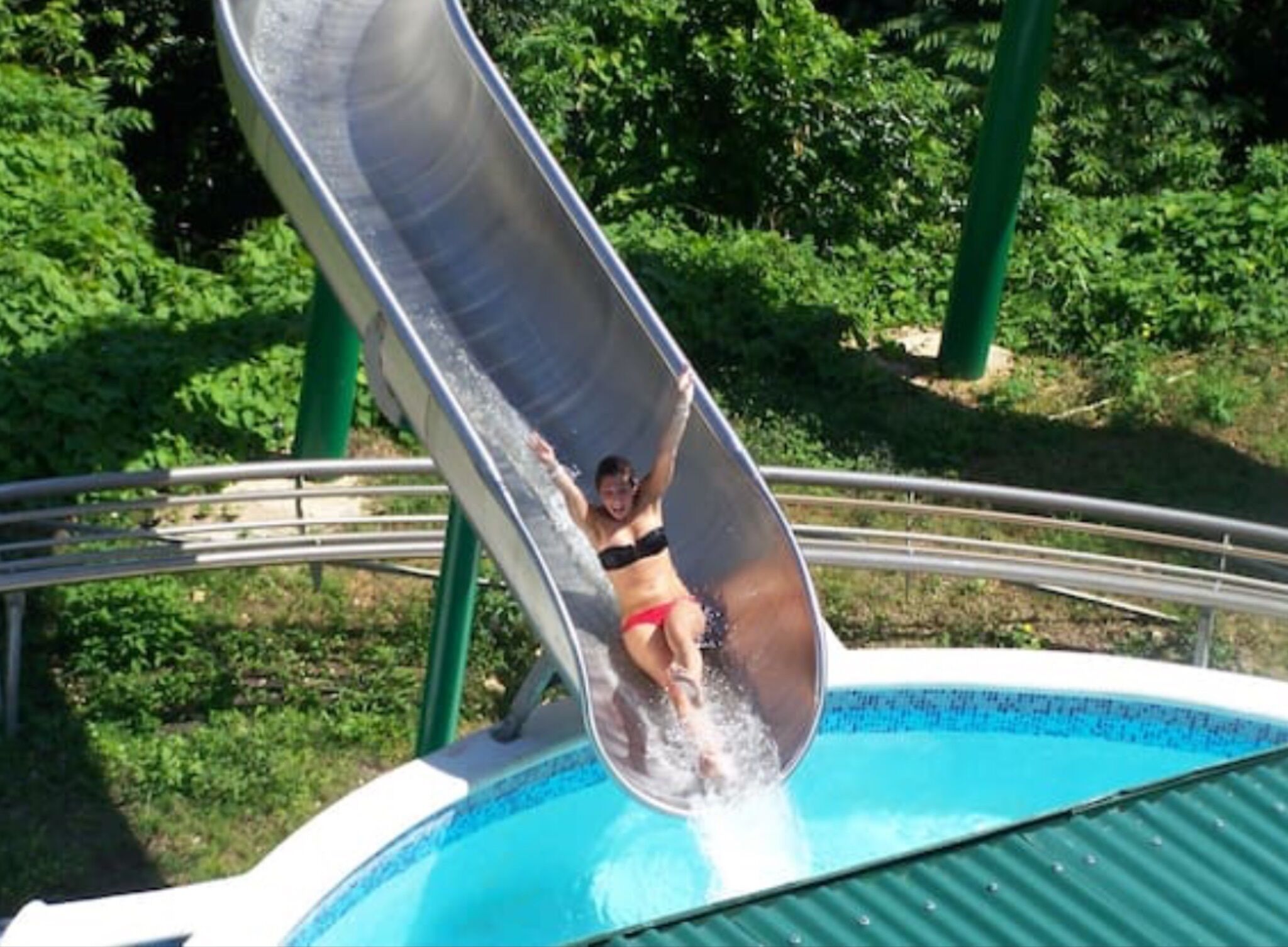 Una persona deslizándose por un tobogán acuático hacia una piscina.