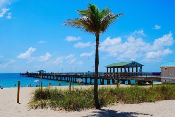 Enjoy a serene beach experience with a pier stretching into the calm waters.