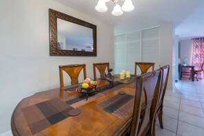 Enjoy meals in this elegant dining area with a wooden table, comfortable chairs, and a large mirror above.