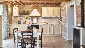 A rustic kitchen with stone walls, wooden beams, and a dining area with a table and chairs. - Apartment in renovated farmhouse in typical Chianti Tuscan village (Villa A Sesta)