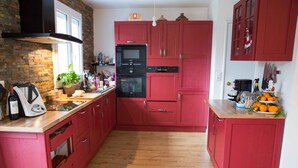 Una cocina con gabinetes rojos, pared de ladrillo y suelo de madera.