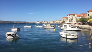 A marina with several boats docked, a clear blue sky, and buildings with red roofs in the background. - Koras Villa - Modern designed villa with heated pool - few steps from the beach  (Kaštel Stari)