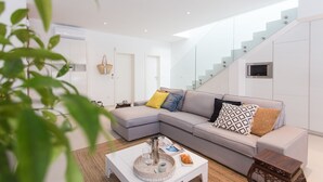 A modern living room with a grey sectional sofa, a white coffee table, and a staircase with glass railings. - Koras Villa - Modern designed villa with heated pool - few steps from the beach  (Kaštel Stari)