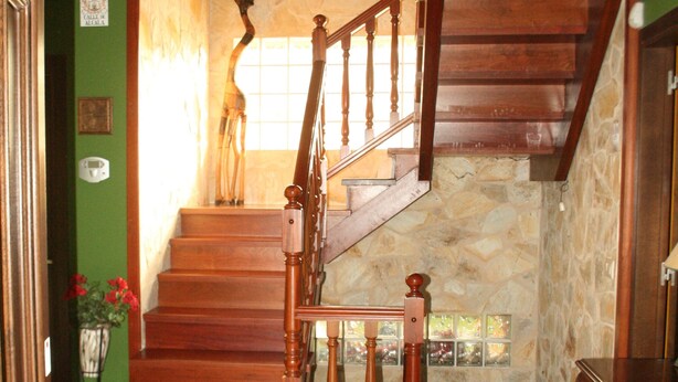 A wooden staircase with a stone wall backdrop, a wooden door, and a chandelier. - Fantastic villa of 200 m2 in Siero (Asturias) (FORFONTIA)