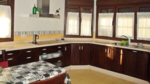 A kitchen with dark wooden cabinets, a sink, and a window with curtains. - Fantastic villa of 200 m2 in Siero (Asturias) (FORFONTIA)