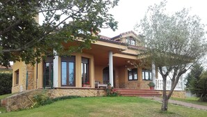 A two-story house with a stone facade, a covered porch, and a well-maintained lawn. - Fantastic villa of 200 m2 in Siero (Asturias) (FORFONTIA)