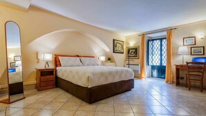 A bedroom with a large bed, a desk, a chair, a mirror, and a door leading to a balcony. - Suite with a Balcony at the Teatro Massimo (Catania)
