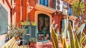 A courtyard with a wooden bench, potted plants, and a door with a lattice design. - Suite with a Balcony at the Teatro Massimo (Catania)