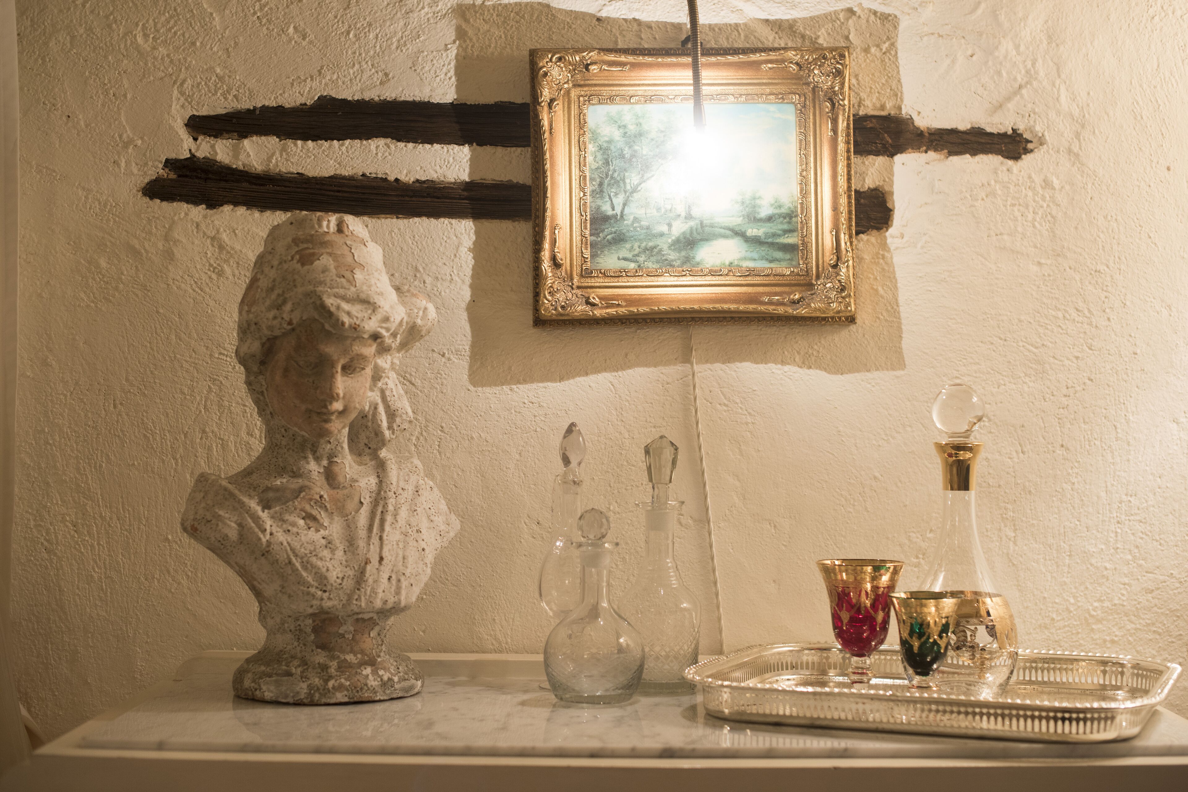 Un buste en marbre, un tableau encadré et des objets de décoration en verre, disposés sur une étagère.